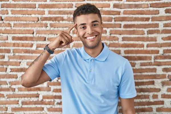 Jovem Brasileiro Sobre Parede Tijolo Sorrindo Apontando Para Cabeça Com — Fotografia de Stock