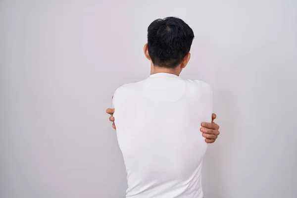 Νεαρός Ασιάτης Στέκεται Πάνω Από Λευκό Φόντο Αγκαλιάζοντας Τον Εαυτό — Φωτογραφία Αρχείου