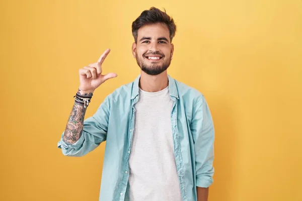 Молодий Іспаномовний Чоловік Татуюваннями Стоять Над Жовтим Тлом Посміхається Впевнено — стокове фото
