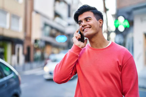 年轻的惊慌失措的男人在街上用智能手机自信地微笑着 — 图库照片