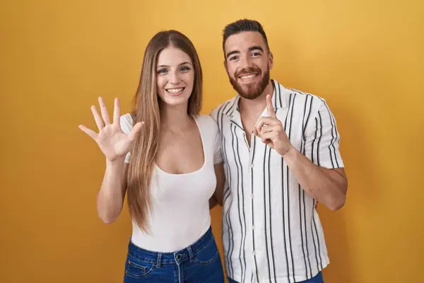 Sarı Arka Planda Duran Genç Çift Altı Numaralı Parmaklarıyla Gülümseyerek — Stok fotoğraf