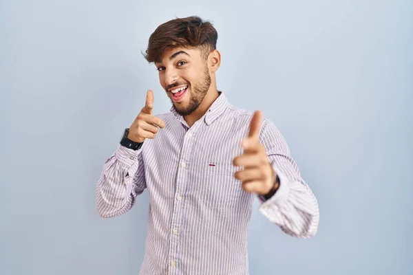 幸福と面白い顔を持つカメラに指を指して青い背景の上に立ってひげを持つアラブ人の男 良いエネルギーと振動は — ストック写真