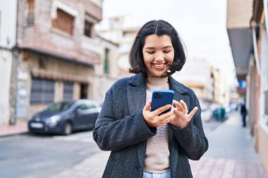 Sokakta akıllı telefon kullanan kendine güvenen genç bir kadın.