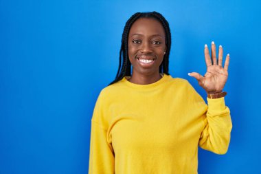 Beautiful black woman standing over blue background showing and pointing up with fingers number five while smiling confident and happy. 