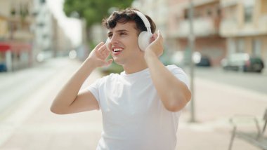 Non binary man listening to music standing at park