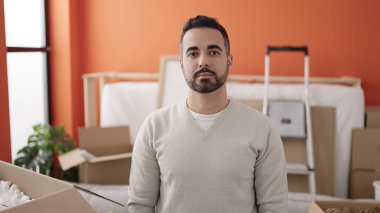 Young hispanic man standing with relaxed expression at new home