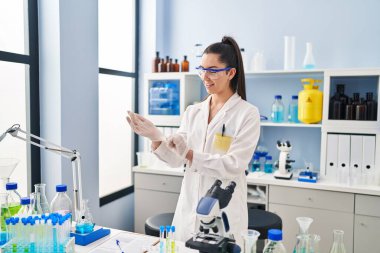 Genç ve güzel İspanyol bilim adamı. Laboratuvarda eldiven takarak gülümsüyor.