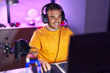 Oyun odasında bilgisayar kullanarak video oyunu oynayan İspanyol asıllı genç adam.