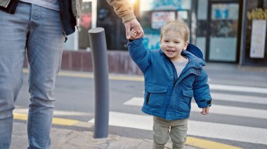 Beyaz çocuk sokakta babamla el ele tutuşurken gülümsüyor.