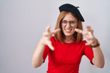 Genç kızıl saçlı, gözlüklü ve bereli bir kadın öfkeden kudurmuş, boğazını sıkmaya çalışan, deli gibi bağıran 