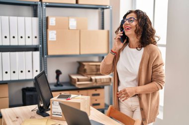 Middle age hispanic woman working speaking on the phone at ecommerce