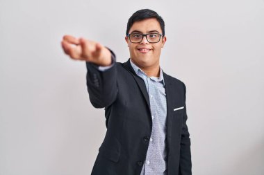 Down sendromlu genç İspanyol bir adam iş stili giyiniyor. Dostça gülümsüyor. Karşılama ve hoş geldin demek için tokalaşıyor. başarılı iş. 