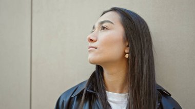 Genç, güzel İspanyol kadın, izole edilmiş beyaz arka planda ciddi bir ifadeyle yan tarafa bakıyor.