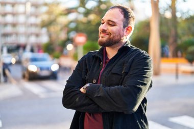 Young hispanic man smiling confident standing with arms crossed gesture at street