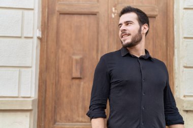 Young hispanic man smiling confident looking to the side at street