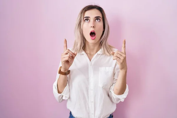 Young Beautiful Woman Standing Pink Background Amazed Surprised Looking Pointing — Foto de Stock