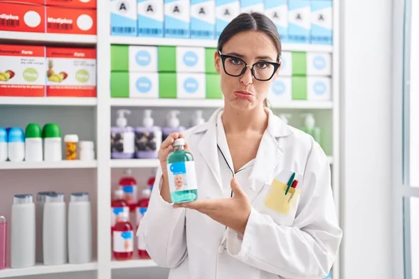 Mujer Morena Trabajando Farmacia Sosteniendo Jarabe Para Tos Deprimida Preocupada — Foto de Stock