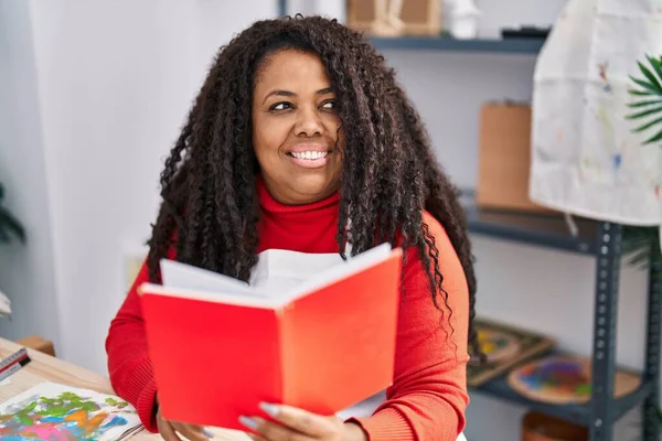 African American Woman Artist Smiling Confident Reading Book Art Studio —  Fotos de Stock