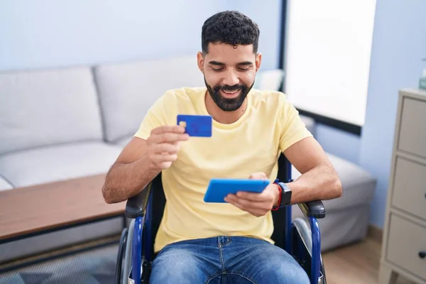 Young Arab Man Using Touchpad Credit Card Sitting Wheelchair Home — Stok fotoğraf
