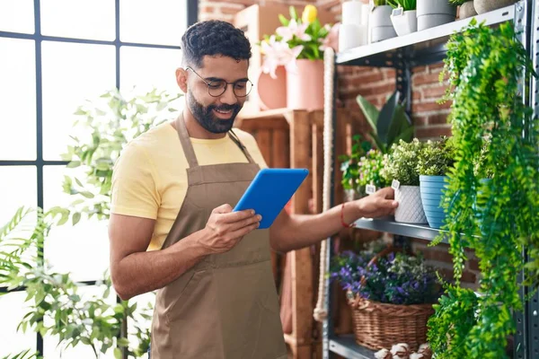 Young arab man florist smiling confident using touchpad at florist