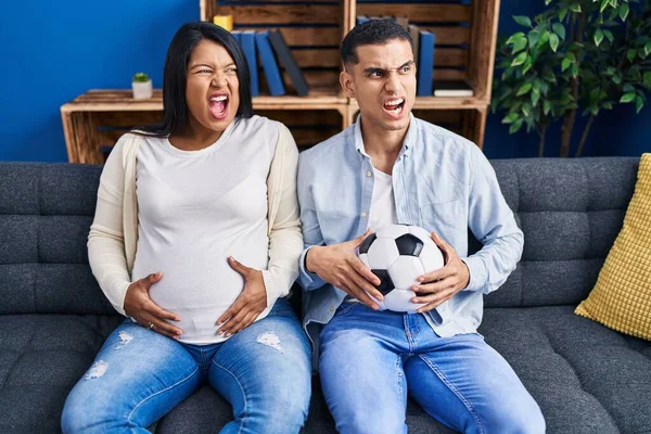 Young Hispanic Couple Expecting Baby Sitting Sofa Holding Ball Tummy — Stock Photo, Image
