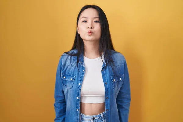 Joven Mujer Asiática Pie Sobre Fondo Amarillo Mirando Cámara Soplando —  Fotos de Stock