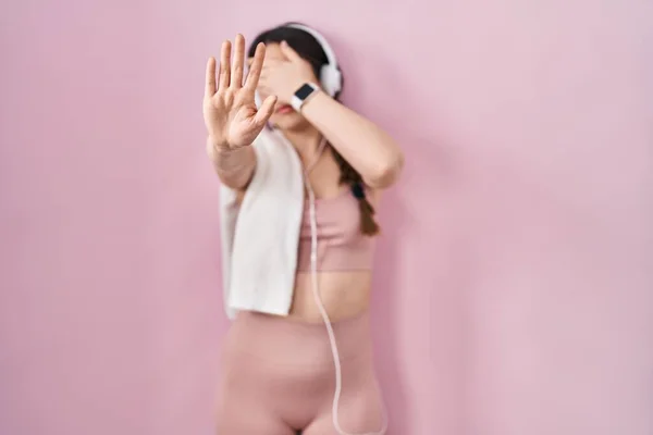 Młoda Brunetka Ubrana Odzież Sportową Słuchawki Zasłaniające Oczy Dłońmi Wykonująca — Zdjęcie stockowe