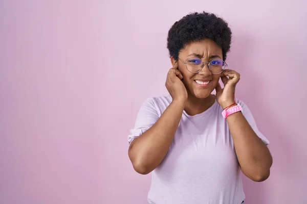 Mladá Afroameričanka Stojící Nad Růžovým Pozadím Zakrývající Uši Prsty Otráveným — Stock fotografie