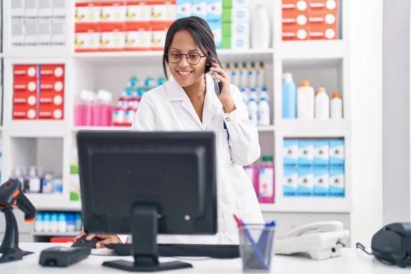 Young Hispanic Woman Pharmacist Talking Smartphone Using Computer Pharmacy — Foto Stock