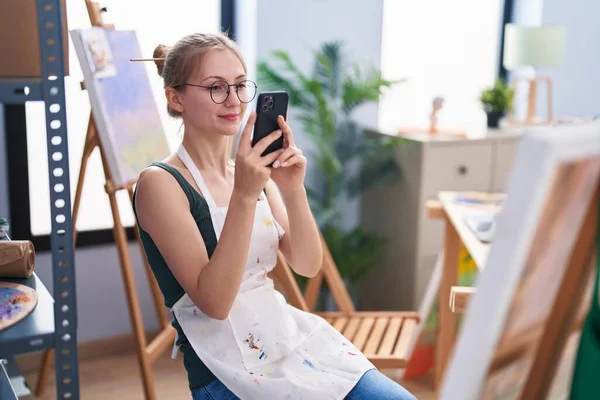若い白人女性アーティストがアートスタジオで絵を描くために写真を撮る — ストック写真