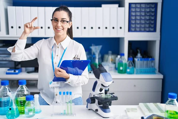 Young Brunette Woman Working Scientist Laboratory Smiling Confident Gesturing Hand — Stock Photo, Image