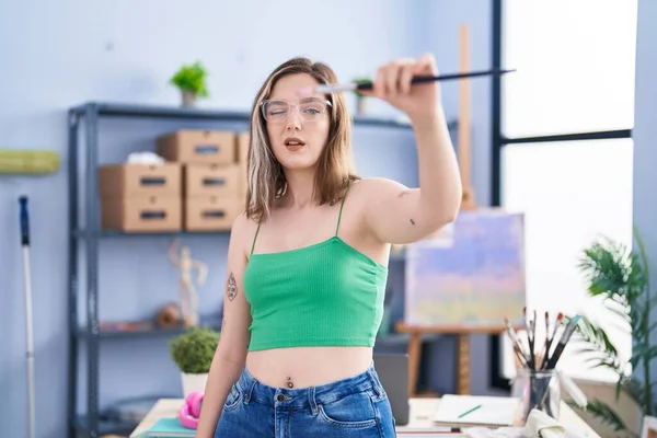 年轻的女艺术家在艺术工作室拿着画笔 — 图库照片