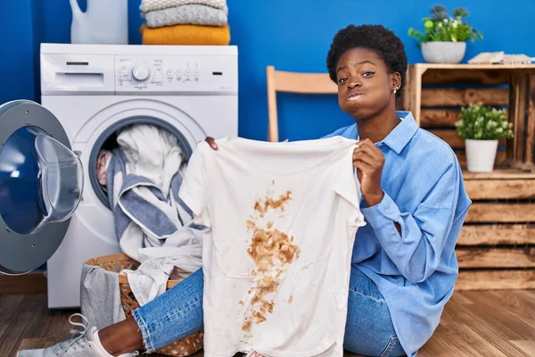 非洲裔美国女人拿着T恤 脸上沾满了肮脏的污渍 满脸滑稽 嘴被空气吹胀 — 图库照片