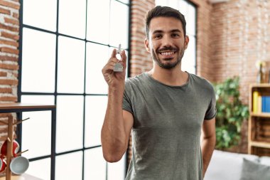 Genç İspanyol adam gülümsüyor. Yeni evin anahtarını elinde tutuyor.