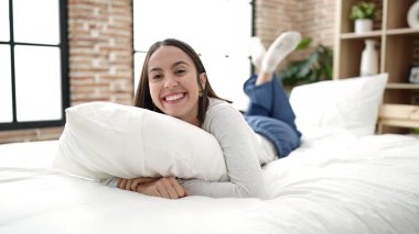 Genç ve güzel İspanyol kadın yatak odasında yastığa sarılıyor.