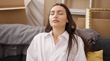 Genç, güzel, İspanyol bir kadın kanepeye oturmuş yeni evinde nefes alıyor.