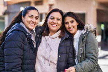 Üç kadın anne ve kız sokakta birbirlerine sarılıyorlar.