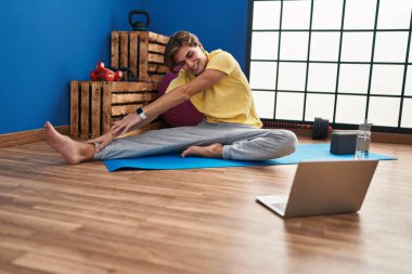 Young caucasian man smiling confident having online stretching class at sport center