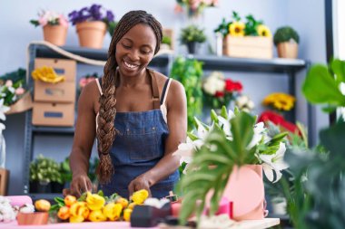 African american woman florist make bouquet of flowers at flower shop