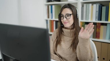 Güzel İspanyol bayan öğrenci kütüphane üniversitesinde video araması yaptığından emin bir şekilde gülümsüyor.