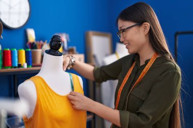 Çinli kadın terzi dikiş atölyesinde kendinden emin bir şekilde gömleğini ölçüyor.