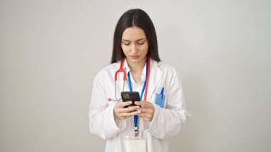 Genç, güzel İspanyol kadın doktor izole edilmiş beyaz arka plan üzerinde akıllı telefon kullanıyor.