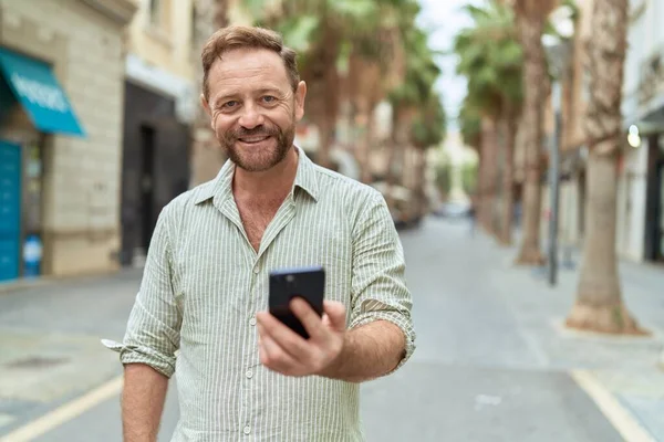 中年人在街上用智能手机充满自信地微笑 — 图库照片