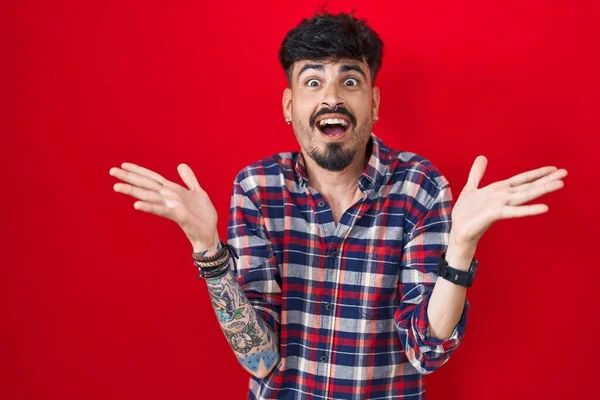 Junger Hispanischer Mann Mit Bart Steht Vor Rotem Hintergrund Und — Stockfoto