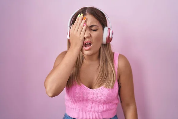 若いブロンドの女性は 半分の顔 口を手で覆い疲れて叫んでヘッドフォンを使用して音楽を聴いています 痛みで顔が痛い — ストック写真