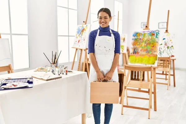 年轻的拉丁女人微笑着 自信地拿着画公文包在艺术工作室里 — 图库照片
