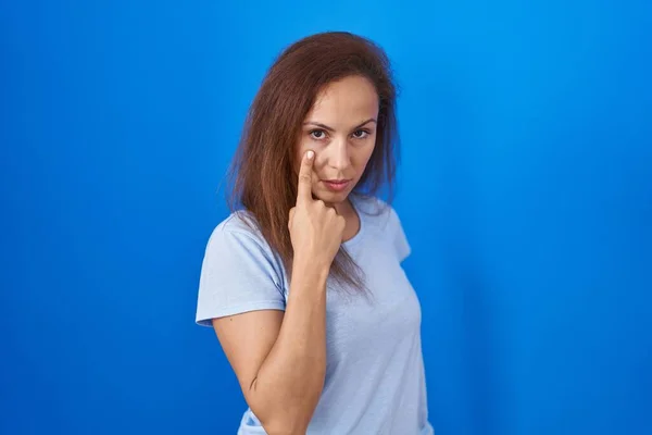 Brunette Vrouw Staan Blauwe Achtergrond Wijzen Naar Het Oog Kijken — Stockfoto