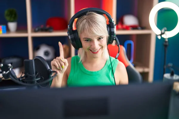 Mladá Běloška Hrající Videohry Sluchátky Usmívající Myšlenkou Nebo Otázkou Ukazující — Stock fotografie