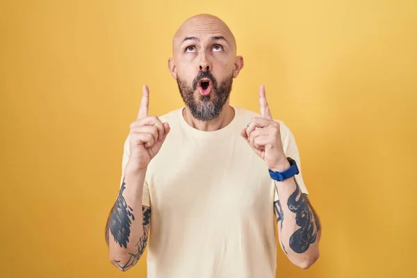Spanyol Férfi Tetoválásokkal Áll Sárga Háttér Csodálkozva Meglepve Néz Fel — Stock Fotó