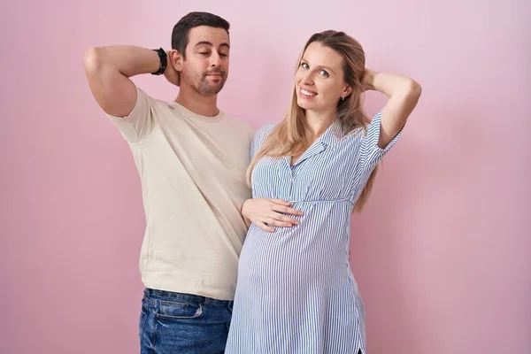 Casal Jovem Esperando Bebê Sobre Fundo Rosa Sorrindo Confiante Tocando — Fotografia de Stock